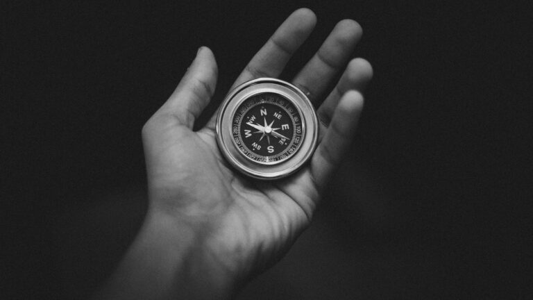 a black and white picture of an upturned hand holding a compass